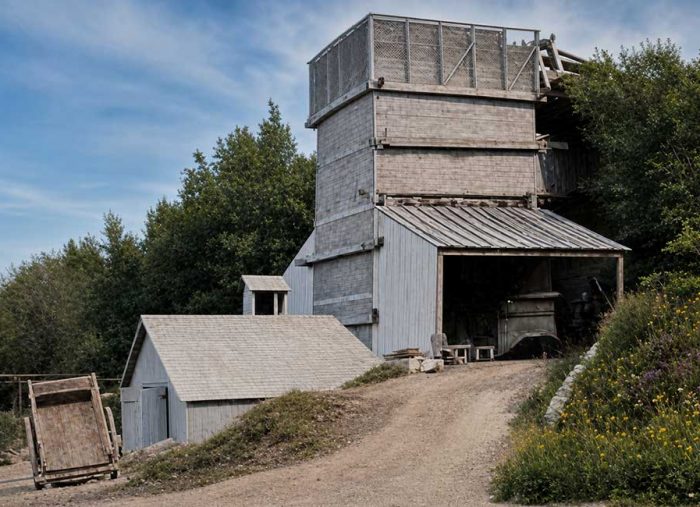 Limehouse. Lime Kilns. 1905. Old weathered grain silo and sheds on a dirt driveway, with trees and wildflowers nearby.